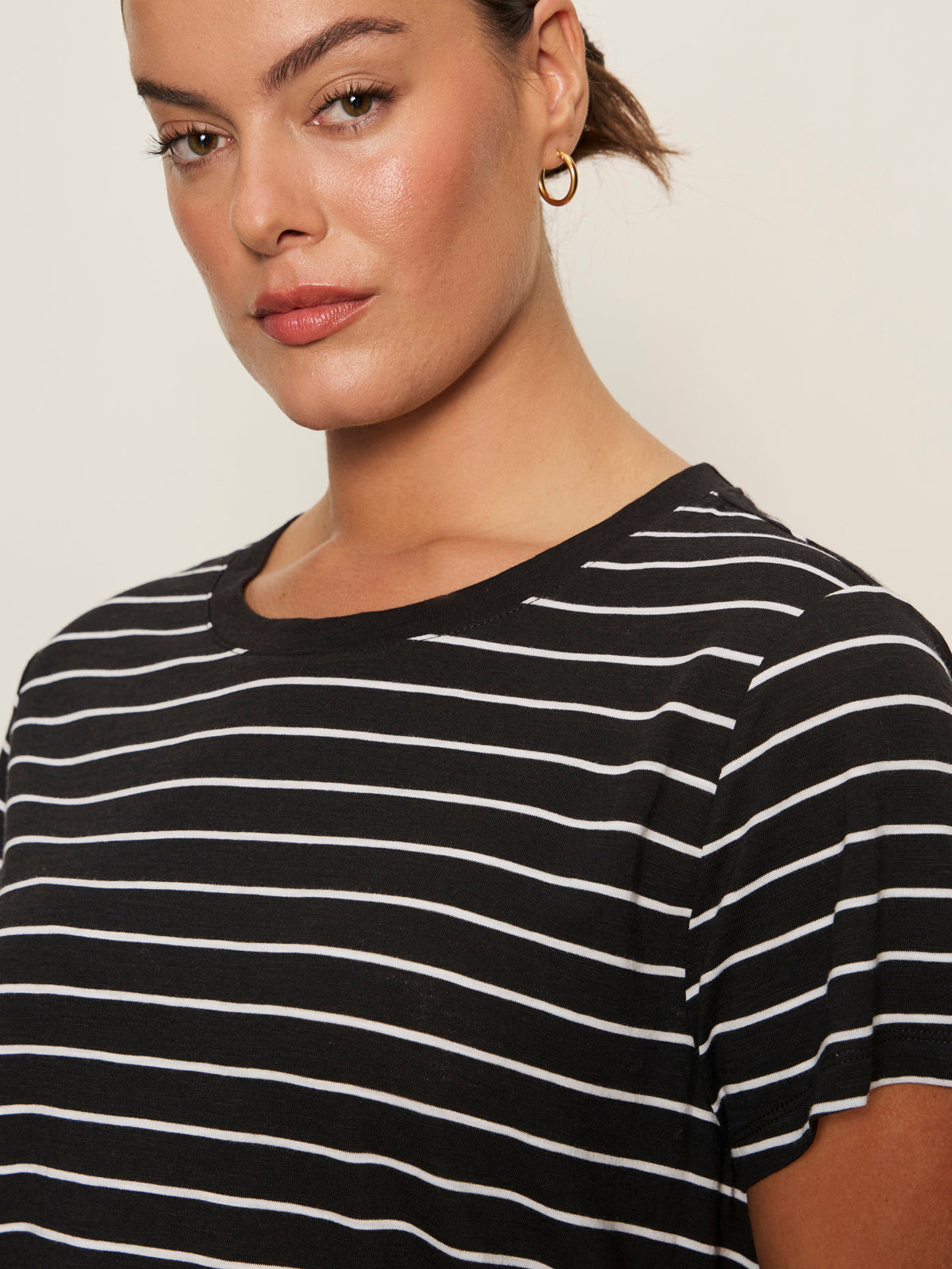 A woman with brown hair and gold hoop earrings confidently models the Sanctuary Clothing 'the perfect tee white black stripe 6'—a black T-shirt with white stripes—against a plain background.