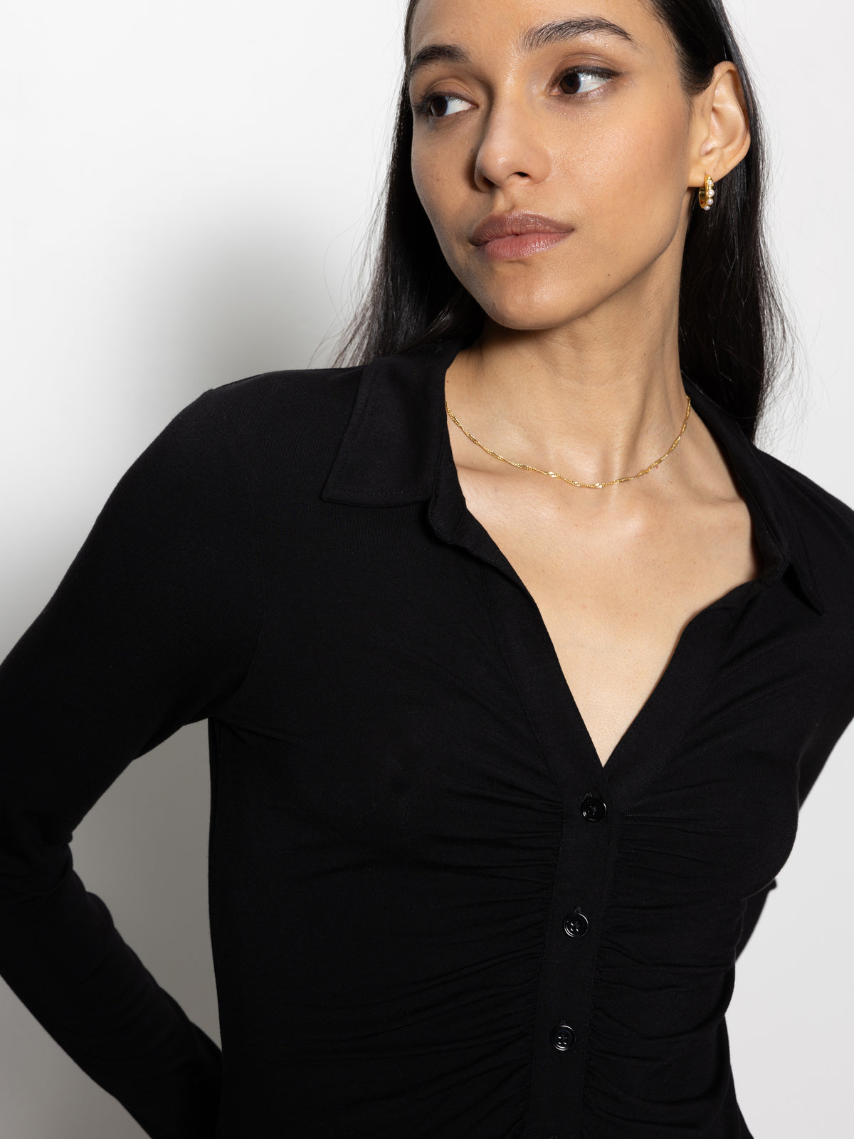 A person with long dark hair wears the "dreamgirl button up black" by Sanctuary Clothing, paired with gold jewelry, and looks to the side against a plain white background.
