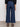 A person stands against a plain background, wearing the Sanctuary Clothing league crop plot twist top with wide-leg blue jeans and black open-toe sandals. The image shows the back view from shoulders to feet.